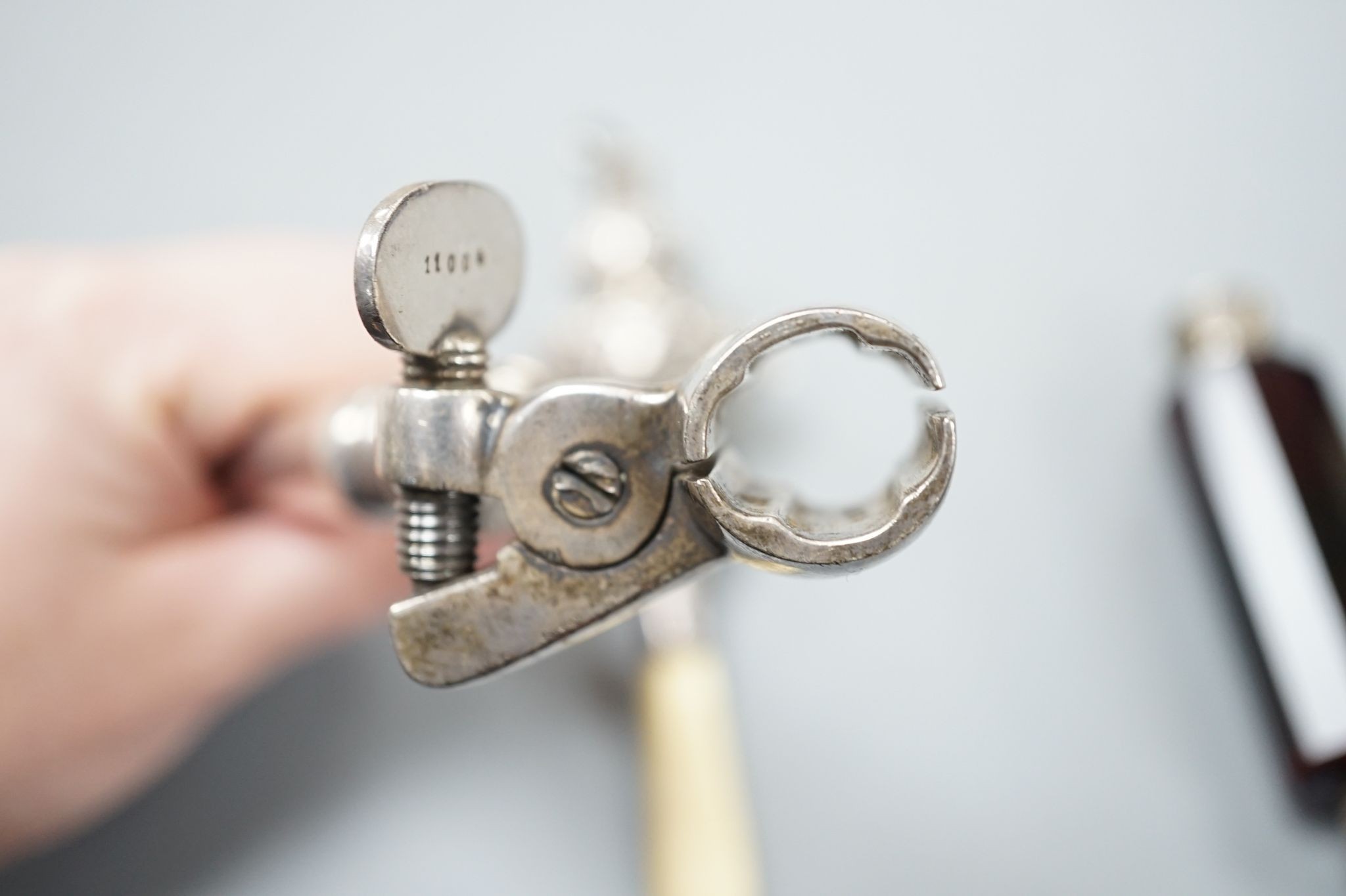 A silver mounted rattle, a white metal mounted double ended ruby glass cent bottle and a silver plated handled roast joint holder.